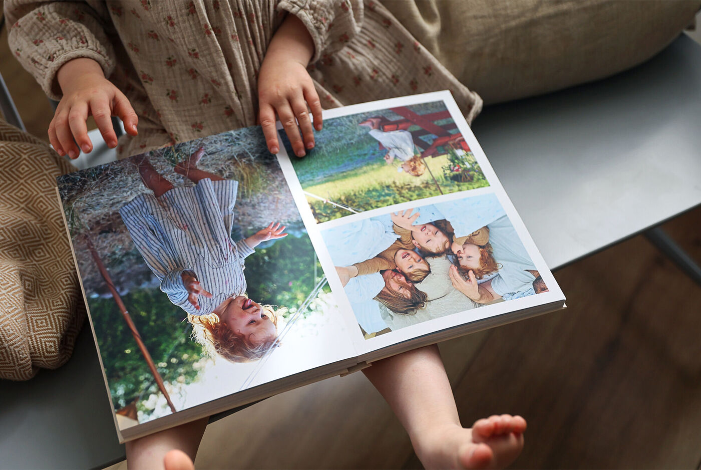 Et barn holder en åben fotobog med familiebilleder og smukke udendørsminder.